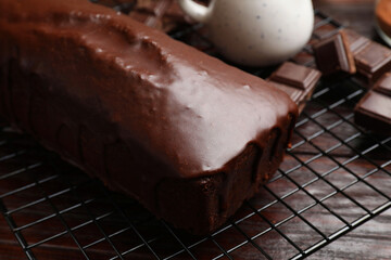 Tasty sponge cake and pieces of chocolate on wooden table, closeup
