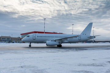 Fototapeta premium White passenger aircraft taxiing on the airport at winter