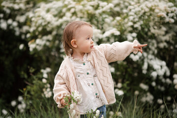 Cute baby girl 2-3 year old standing in meadow with flowers outdoors. Springtime. Childhood.