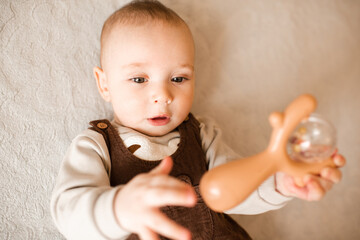 Cute baby boy 3-6 month old lying in bed close up with toy. Childhood.