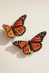 Obraz premium Two orange butterflies sit on a white surface