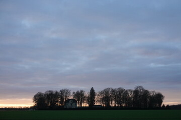 einsame Villa, von Bäumen umgeben, bei Sonnenuntergang