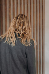 Back view of a blonde woman with wavy hair in grey blazer