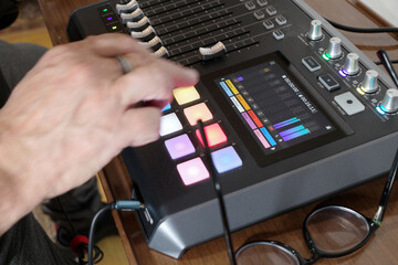 The hands of a man who operates a mixer that can mix and record incoming material with other sounds...
