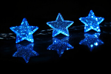 Obraz premium three illuminated blue stars with glittering textures reflected on a glossy black surface creating a festive ambiance 