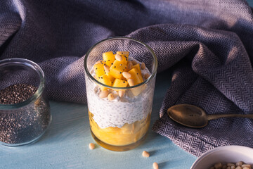 Pudding made from chia seeds, mango puree, pine nuts and yogurt on the table with a spoon and a...