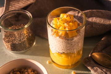 Pudding made from chia seeds, mango puree, pine nuts and yogurt on the table with a spoon and a...