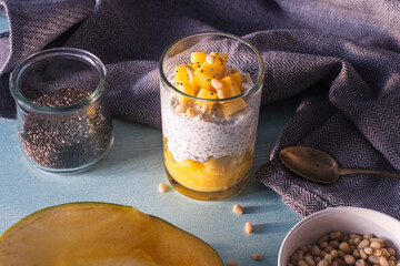 Pudding made from chia seeds, mango puree, pine nuts and yogurt on the table with a spoon and a...
