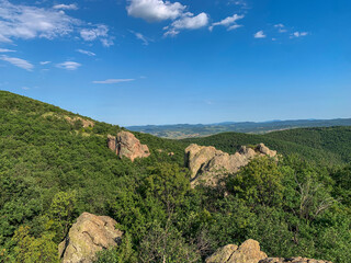 The majestic Rhodope Mountains stretch out beneath a vibrant blue sky, their rugged peaks and lush forests creating a breathtaking panorama.