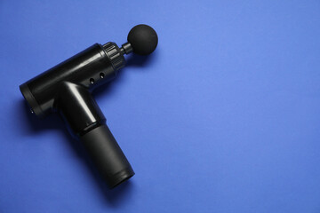One black percussive massager on blue background, above view. Space for text