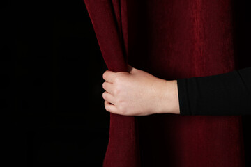 Woman opening red front curtains in theatre, closeup. Space for text