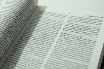 Open Holy Bible in English language on table, closeup