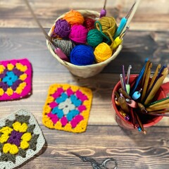 Crochet granny square, clews and hook on crochet blanket background photo	
