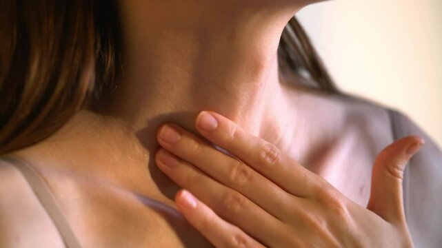Close-up of an unrecognizable woman touching her neck. Endocrine health prevention. Diseases of the thyroid gland. Cancer screening. Endocrinology. Concept of medicine and health care. 