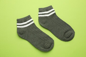 Pair of soft socks on light green background, top view