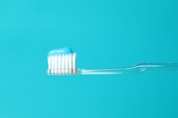 Toothbrush with toothpaste in air on light blue background, closeup