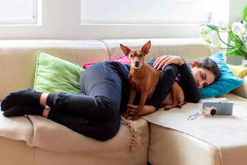 A cute young  girl in bed hugging a the pinscher breed. A teenager is napping in bed hugging her...