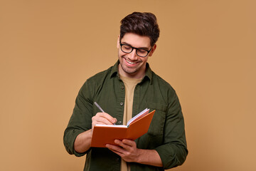 A Young Man Deep in Thought, Vividly Writing in His Notebook Against a Simple Background
