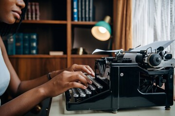 Young Black Woman Typing on a Vintage Typewriter. Retro Office Setting with Classic Equipment, Emphasizing the Art of Writing and Storytelling