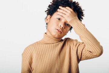 Young african american boy with hands on head, expressing contemplation and innocence in a...