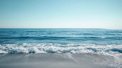 Serene Ocean Horizon with Gentle Blue Waves Lapping Against a Sandy Shore Under a Bright Clear Sky