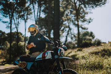 Hombre con barba y estilo alternativo con moto de campo en paso de bosque 