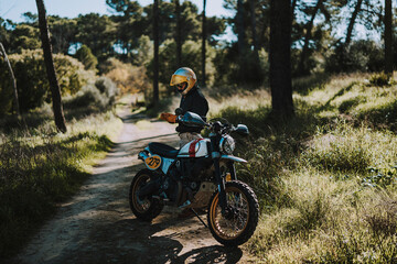 Fototapeta premium Hombre con barba y estilo alternativo con moto de campo en paso de bosque 
