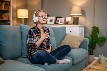 Obraz premium Mature senior woman practice guided meditation manifestation at home