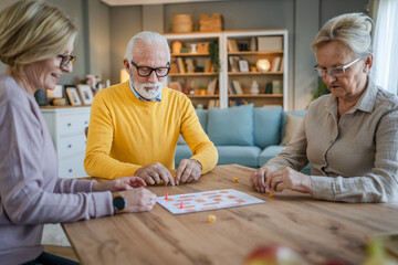 Group of people senior man and women play leisure board game at home