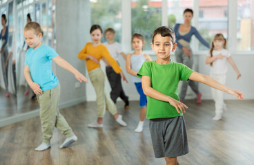 Group of happy preteen children with female teacher practicing hip hop in modern dance studio