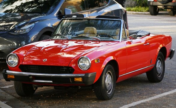 Winter Haven, Florida, U.S.A - November 10, 2024 - A vibrant red classic 1981 Fiat 124 Spider 2000 Turbo convertible, gleaming in the sunlight