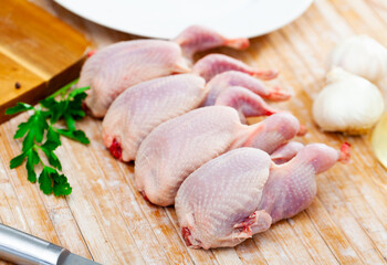 Natural raw gutted partridges on wooden surface of kitchen table with seasonings and greens....