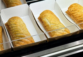 Sausage rolls displayed for sale in cardboard trays