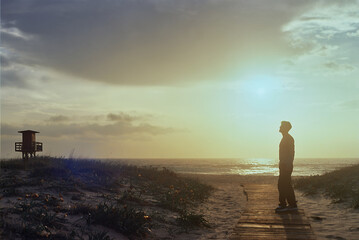 Man walking to the beach at sunset with lifeguard tower in background, analog 35mm © EDER