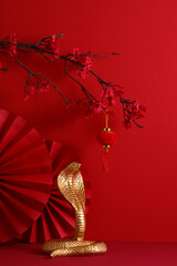 Happy Chinese New Year 2025 year of the snake concept. Golden snake figurine on a red background...