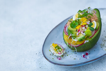 Sałatka z tuńczykiem jajkiem, rzodkiewkami i sałatą ułożona na połówce awokado. © Dorota