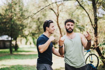 Naklejka premium Two friends share a casual moment in a park setting, surrounded by lush trees. Relaxed vibe and natural connection illustrate friendship and leisure in a tranquil outdoor environment.