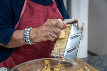 Close-up of adult woman's hands grating green banana on a grater