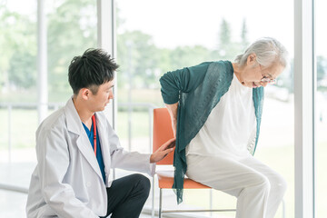 Obraz premium 男性医師に腰痛を訴えるシニア女性 
