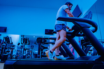 Deportista entrenando en gimnasio sobre cinta de correr.