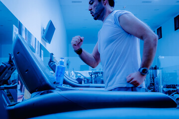 Deportista entrenando en gimnasio sobre cinta de correr.
