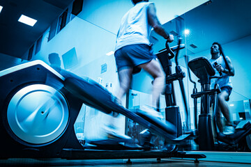 Deportista entrenando en gimnasio sobre bicicleta elíptica.