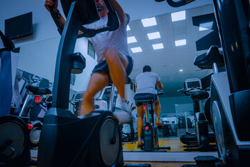 Hombre deportista entrenando en gimnasio sobre bicicleta elíptica.