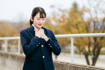 胸に手を当て祈る制服姿の女子高生（願う・希望・夢・合格・願い事）
