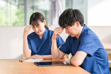 Fototapeta premium スクラブを着た医者・医師・看護師・医療従事者・作業療法士・理学療法士の男女（疲労・過労・人手不足） 