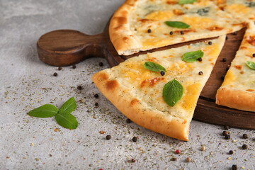 Board with tasty cheese pizza on grey grunge background