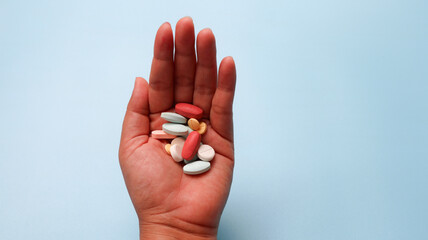 Colorful pills and medicines in the hand isolated on blue background. overdose concept. health care concept