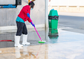 Obraz premium Woman clean floor with mop in factory.