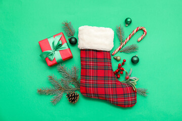 Christmas sock with decor on green background. Top view