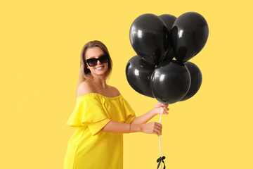 Beautiful young woman with air balloons on yellow background. Black Friday concept